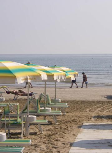 Spiaggia tranquilla con ombrelloni colorati, mare calmo e atmosfera rilassante.