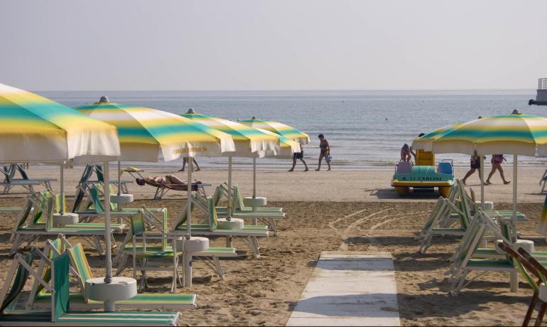 Spiaggia tranquilla con ombrelloni colorati, mare calmo e atmosfera rilassante.